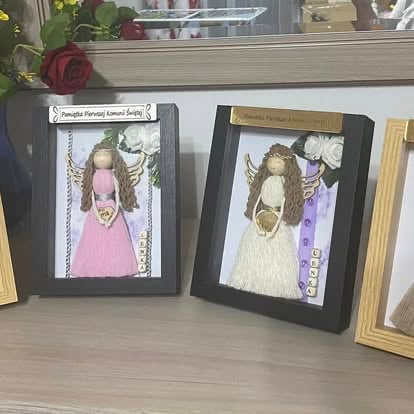 Dzieła dzieci w ramkach na półce z różą i dekoracjami