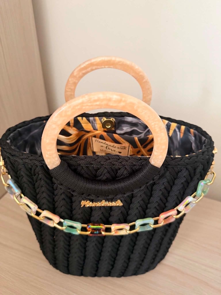 Black quilted handbag with beige wooden handles, decorative beaded trim, and tiger-stripe patterned interior lining