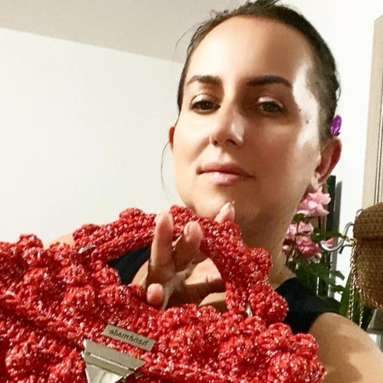 Kobieta z kolorowymi spinkami do włosów trzymająca czerwony dziany sweter